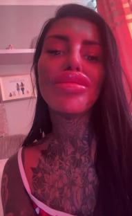 Close-up selfie of a woman with large lips and tattoos.