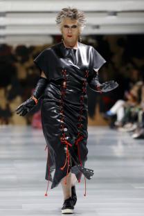 Prue Leith walking a runway in a black leather dress.