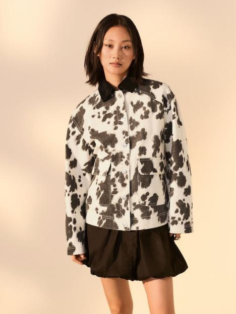 Woman wearing cow-print jacket and black skirt.