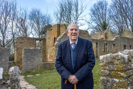 Peter Wellman, the last resident of Tyneham, a World War II ghost village, standing in front of the village ruins.