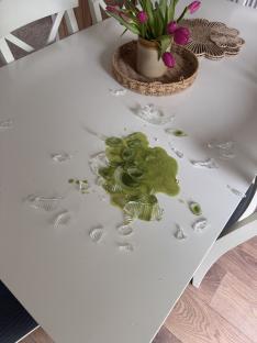 Shattered glass mug and spilled matcha latte on a table.