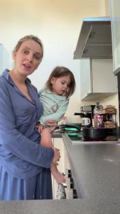 Woman holding toddler in kitchen.