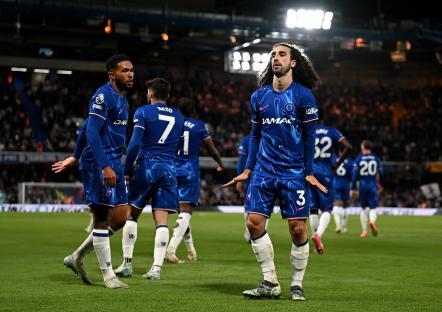 Chelsea players celebrating a goal in front of cheering fans.