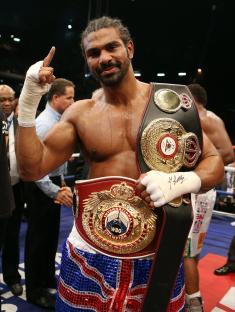 David Haye celebrating a boxing victory, wearing championship belts.