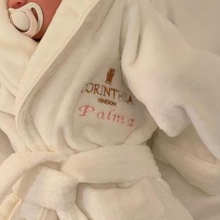 Baby in a Corinthia London bathrobe embroidered with the name Palma.