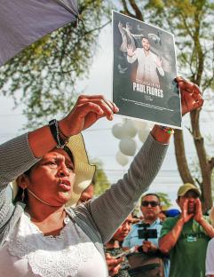 A woman holds a photo of Paul Flores at his funeral in Peru.