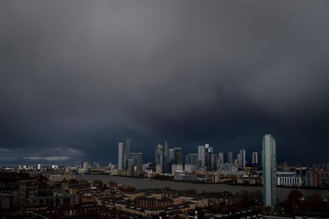 Canary Wharf skyline under a dark, stormy sky.
