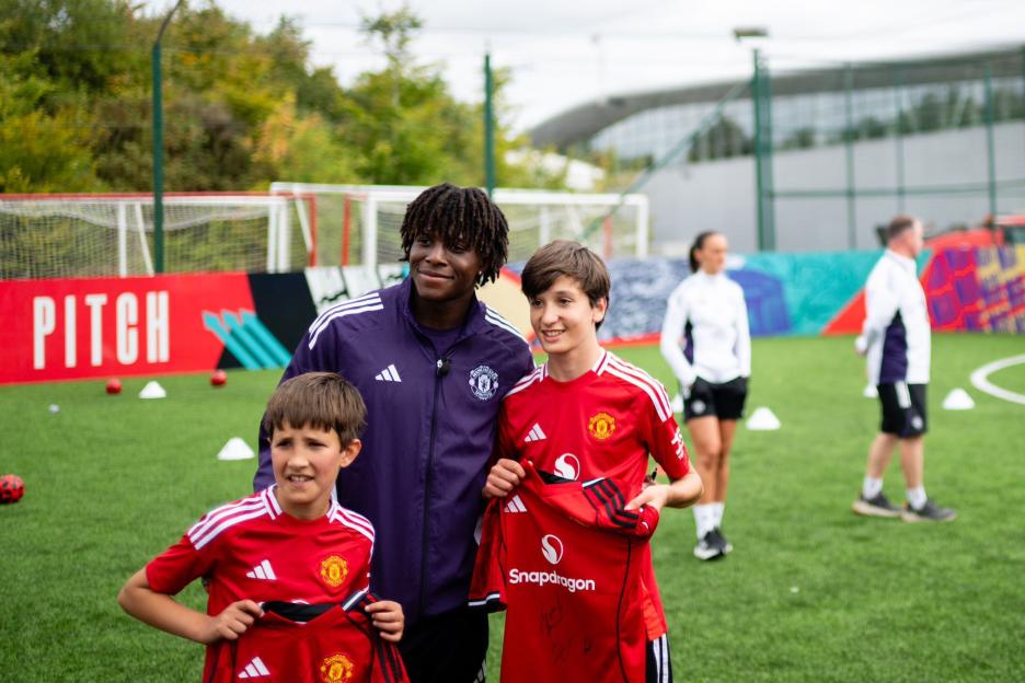 Three young soccer players with Manchester United jerseys.
