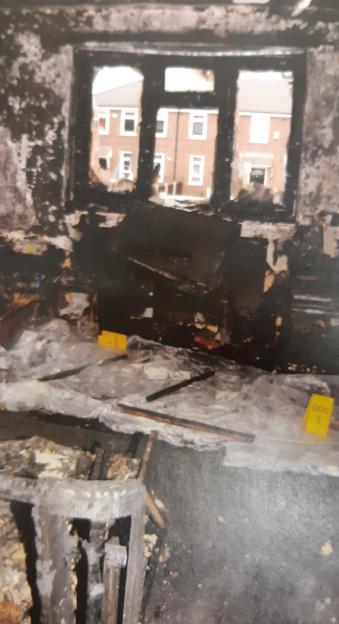Collage of a fire-damaged room with a view of a red-brick building outside the window, and a mugshot of a man with reddish skin and a beard.