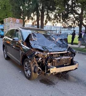 A severely damaged black SUV after hitting a crowd.