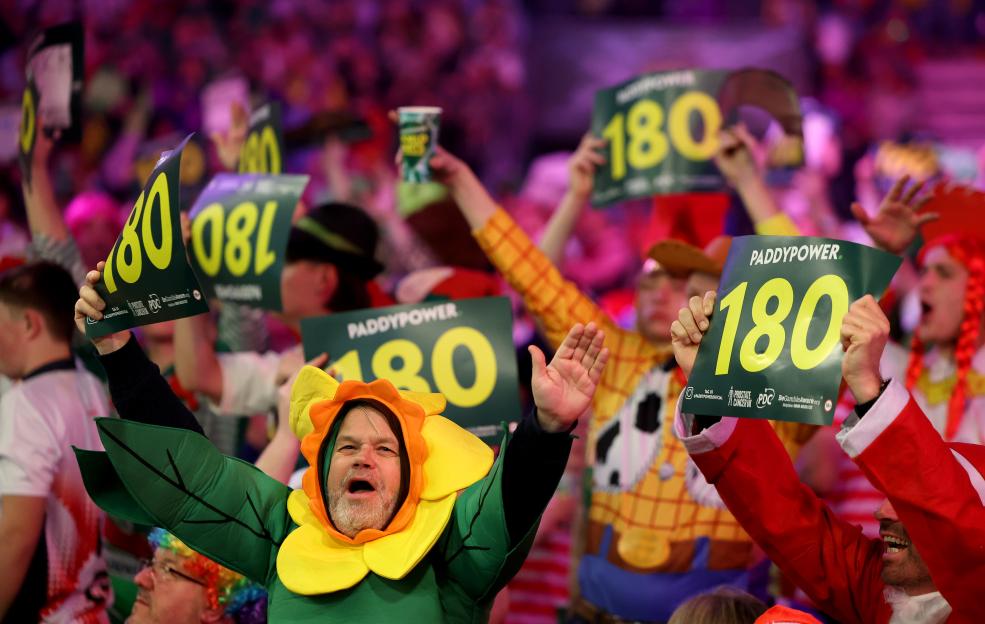 Fans react at the 2023/24 Paddy Power World Darts Championship, holding up signs with "180" on them.