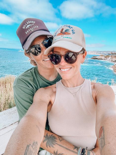 Selfie of a couple embracing outdoors near the ocean.