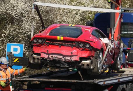 Damaged red Ferrari on a tow truck.