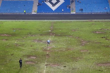 A soccer field littered with trash after a pitch invasion.