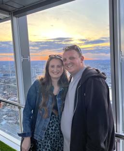 Couple posing for a photo at sunset, overlooking a city.