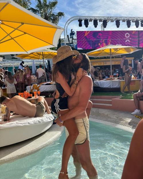 Couple kissing by a pool at a party.