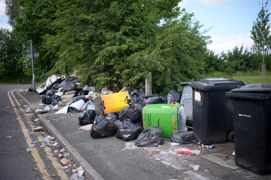 Overflowing bins and rubbish piled on a pavement during a refuse workers' strike.