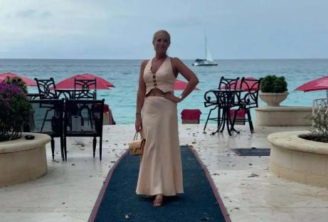 Woman in beige dress walking on a hotel carpet runner.