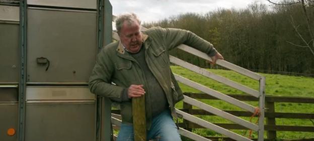 A man leaning on a gate after being attacked by a pig.