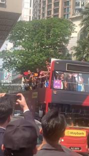 People on a double-decker bus waving to onlookers.