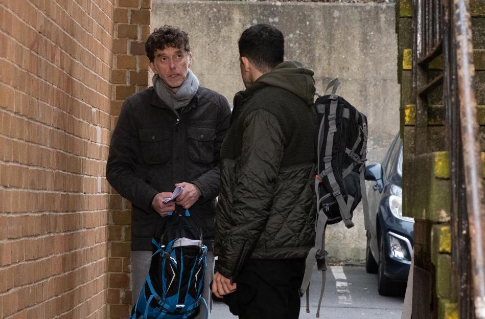 Two men talking in an alleyway.