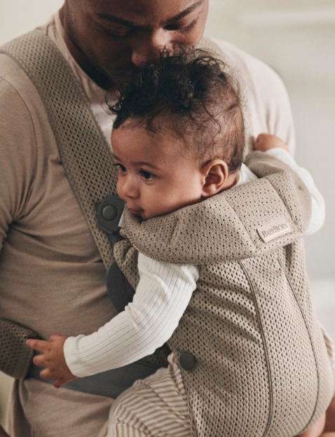 Father holding baby in a BabyBjörn carrier.