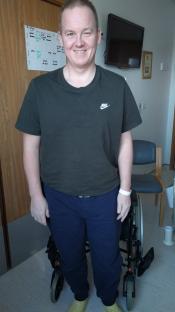 Man standing in a hospital room, near a wheelchair.