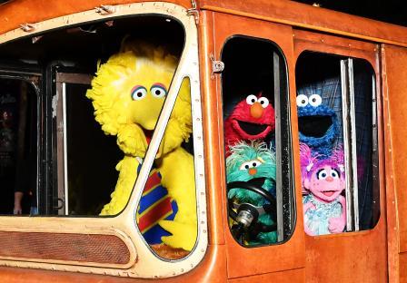 Big Bird, Elmo, Cookie Monster, and Abby Cadabby in a vintage vehicle.