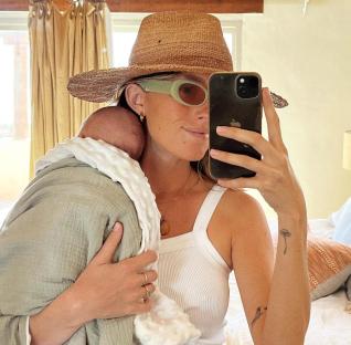Woman holding a baby, taking a selfie.
