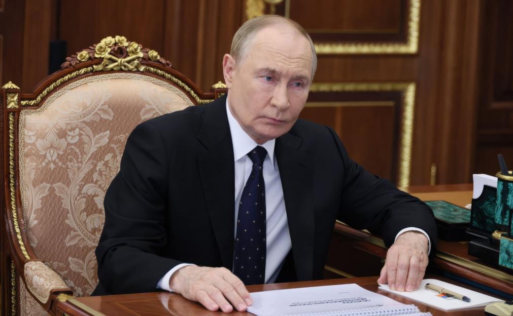 Vladimir Putin listening to a report at a meeting in the Kremlin.