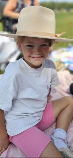 Smiling girl wearing a hat and pink shorts.