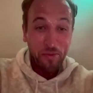 Harry Kane, sweaty and smiling, wearing a light-colored hoodie.