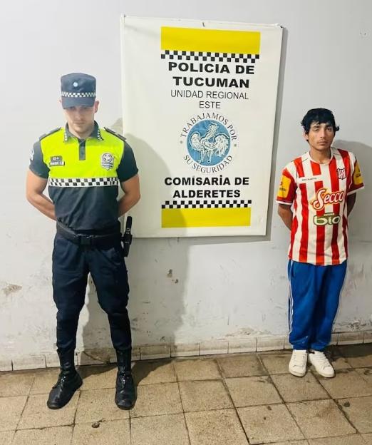 A police officer and a man who was presumed dead standing in front of a sign that reads "Policia de Tucuman".