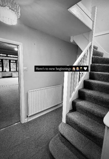 Black and white photo of a hallway with stairs and a radiator.