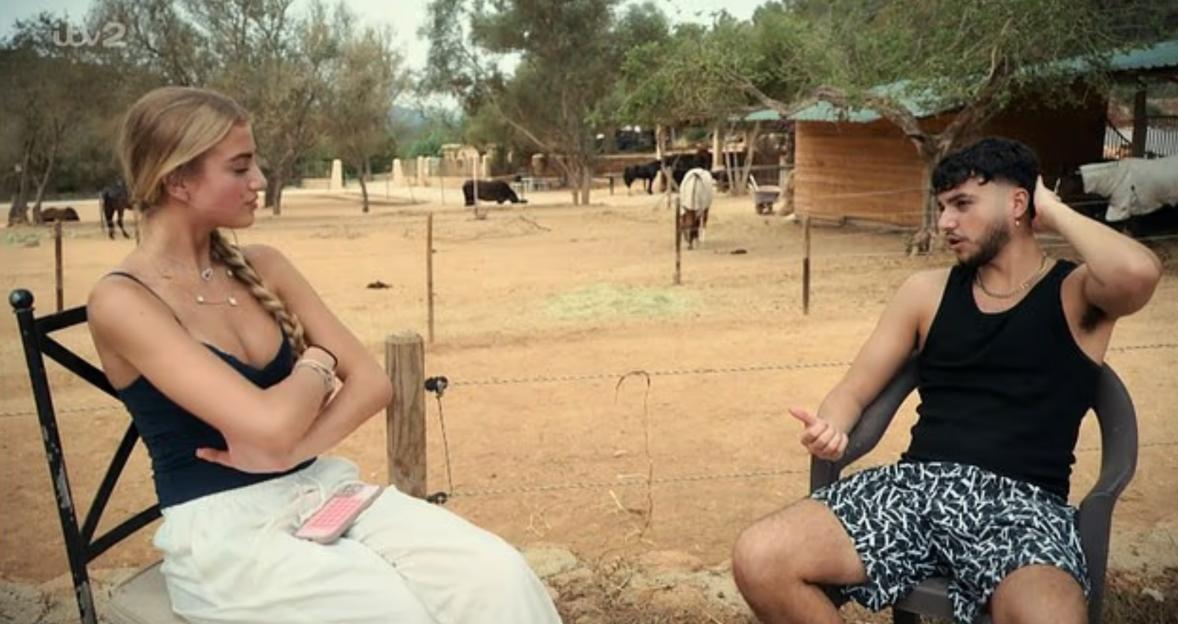 Princess Andre and a young man sit outdoors discussing her experience being held at gunpoint.