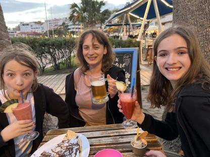 A woman and two girls enjoying drinks and dessert at an outdoor cafe in the Canary Islands.
