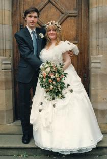 Wedding photo of a bride and groom posing outside a building.