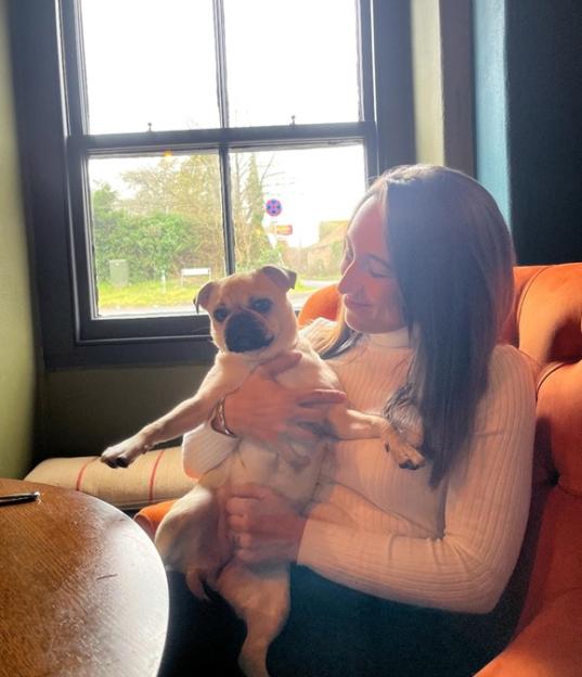 A woman holding a small dog in her lap.
