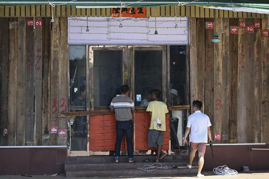 People install wood panels on a restaurant to resist wind ahead of an approaching typhoon.