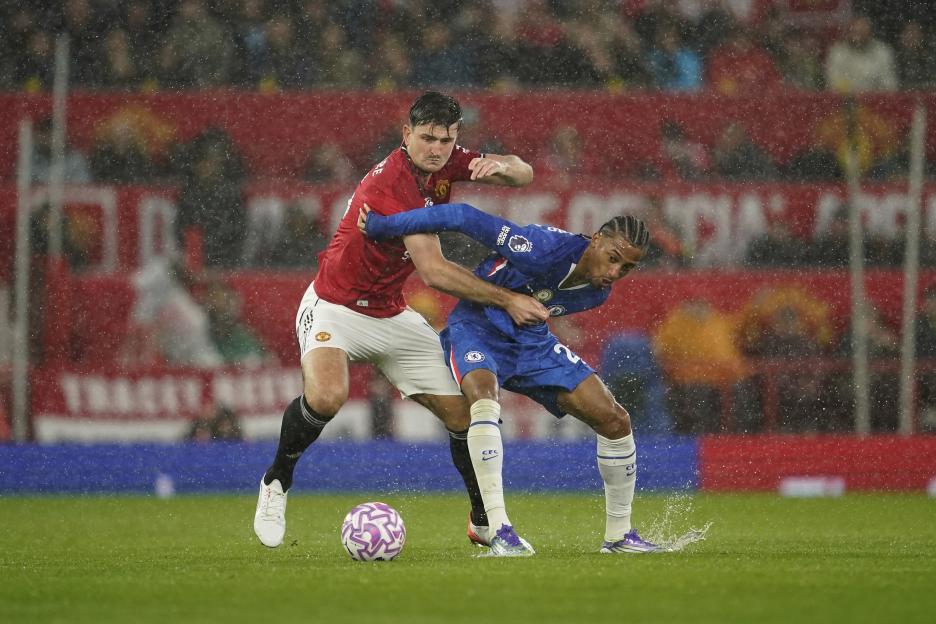 Manchester United's Harry Maguire and Chelsea's Joao Pedro challenge for the ball in the rain.
