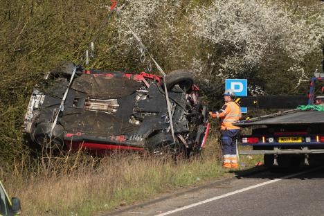 Upside-down red car being recovered by a tow truck.