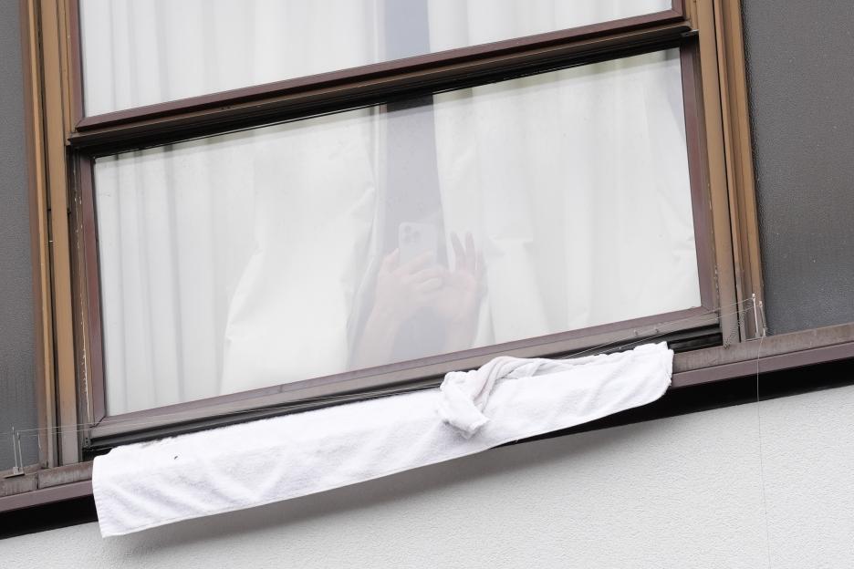 Hotel resident using a phone, seen through a window.