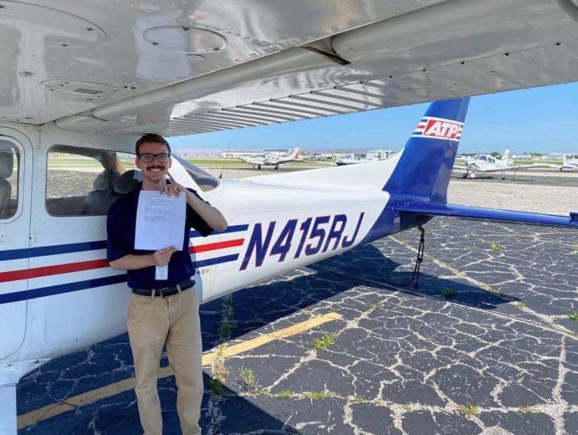 Sam Lilley holding a document in front of a small plane.