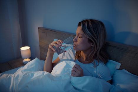 Woman drinking water in bed before sleep.
