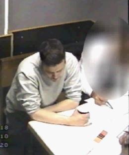 a man sits at a table with the number 18 on the bottom right