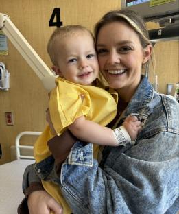 A mother holding her young son in a hospital room.