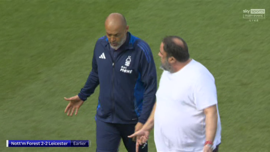 Two soccer coaches talking on the field.