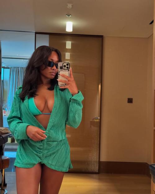 Tolami Benson posing in a green outfit and sunglasses.