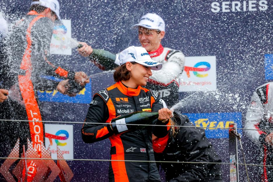 Jamie Chadwick celebrating on the podium with champagne.