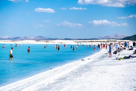 People swimming and relaxing on the white sand beach of Lake Salda, Turkey.